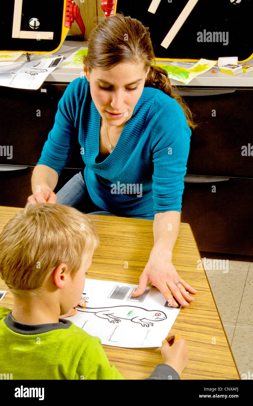 Eine Lehrer hilft Sehbehinderte junge Farbe, die eine Eidechse mit Art ausgelöst, wenn sie durch Berührung in einem speziellen erkennen, benötigt Klasse. Stockfoto