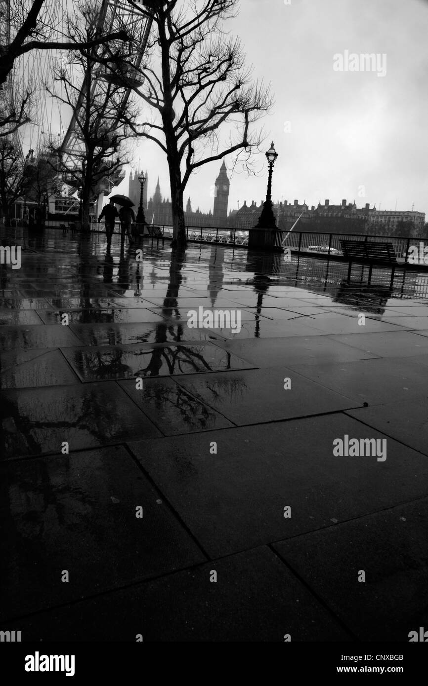 Blick auf die Houses of Parliament und das London Eye aus einer regnerischen Königin Spaziergang, South Bank, London, UK Stockfoto