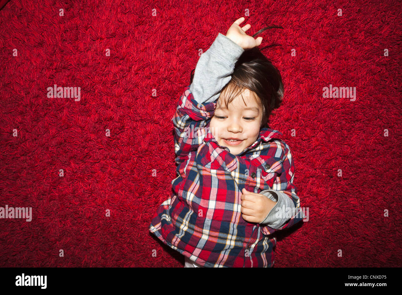 Eine lächelnde junge liegend auf einem roten Teppich Stockfoto