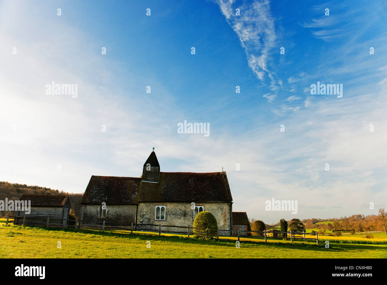 St.-Hubertus Kapelle Idsworth Hampshire am frühen Morgen mit Raps Feld im Hintergrund und blauer Himmel mit Wolken Stockfoto