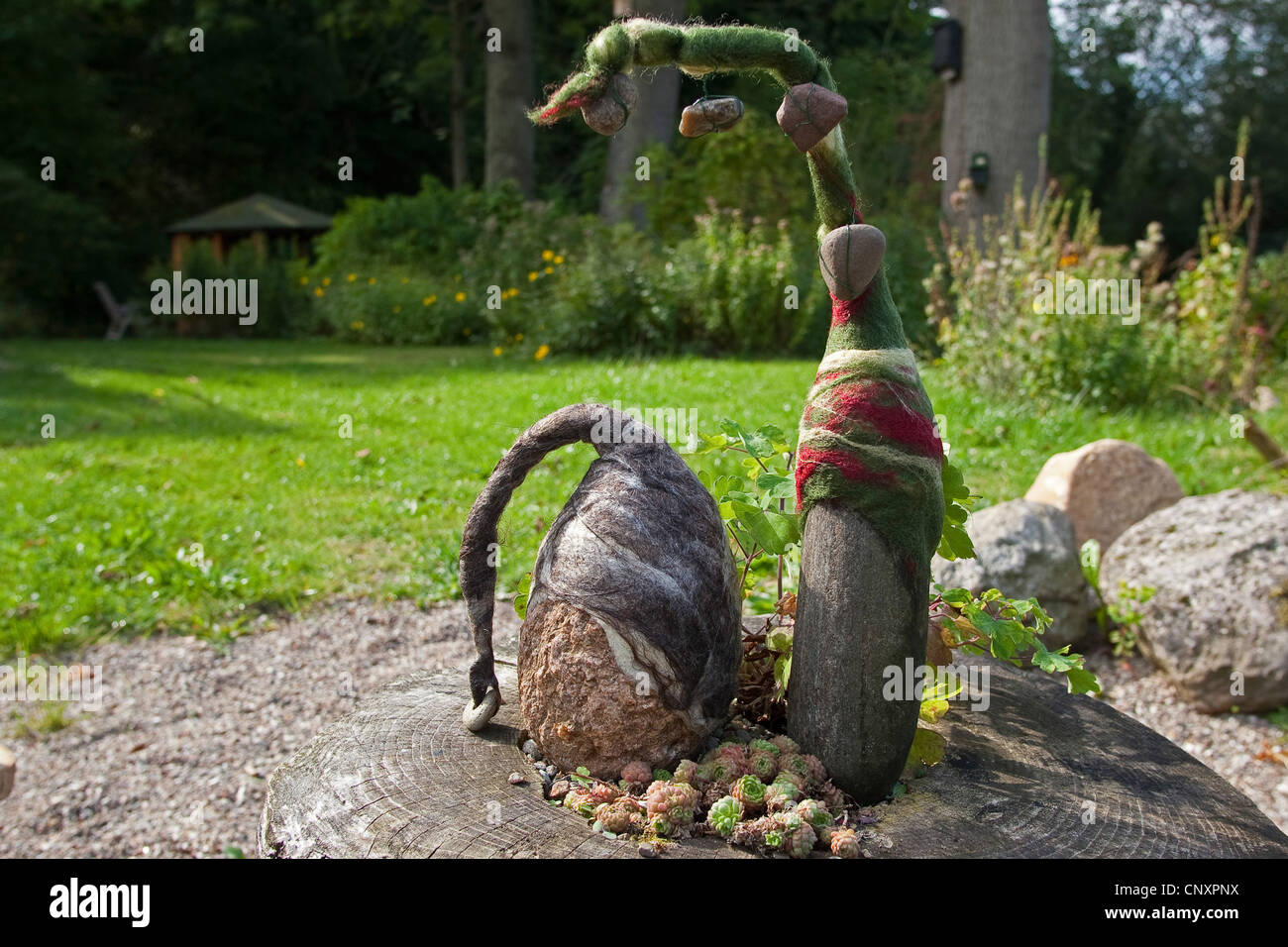 "Filz steinerne Trolle", die als Gartendekoration: zwei Natursteine, ausgestattet mit Kappen der verfilzt Wolle stehen nebeneinander auf einem Baum Haken, Deutschland Stockfoto