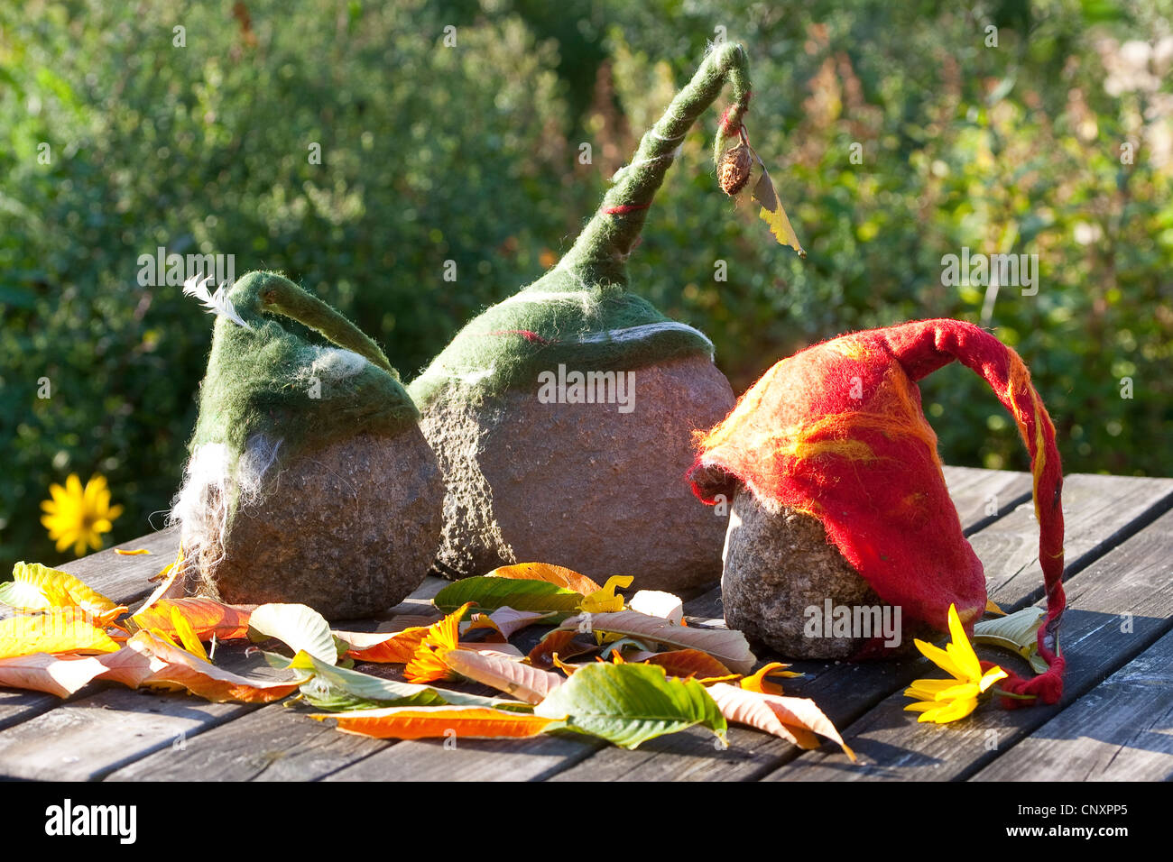 "Filz steinerne Trolle", die als Gartendekoration: drei Natursteine, ausgestattet mit Kappen der verfilzt Wolle stehen nebeneinander auf einem Gartentisch, Deutschland Stockfoto