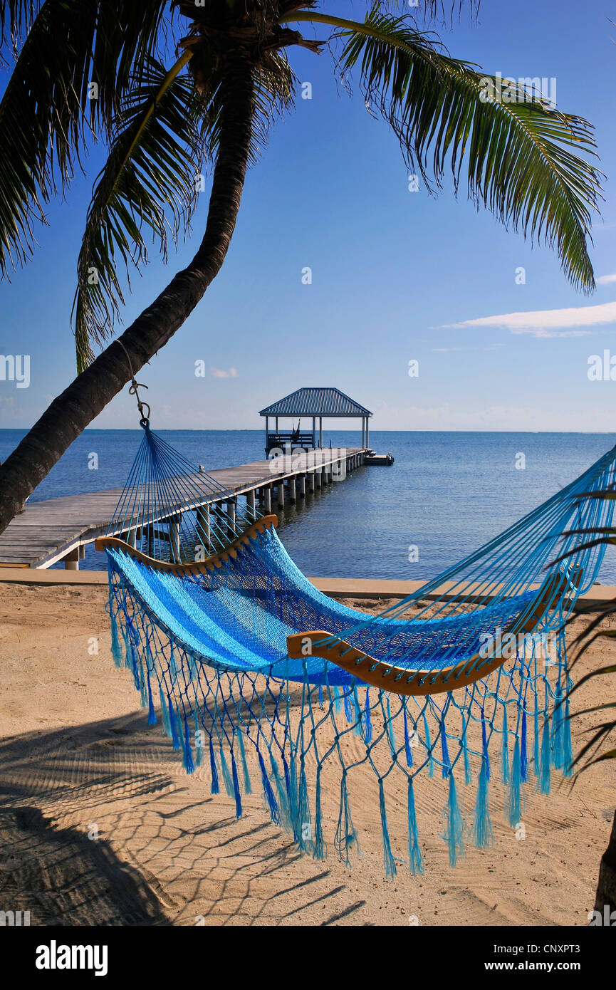 Blick vom Sandstrand über eine Hängematte auf einem Holzsteg führt ins Meer, Belize, Ambergris Caye Stockfoto