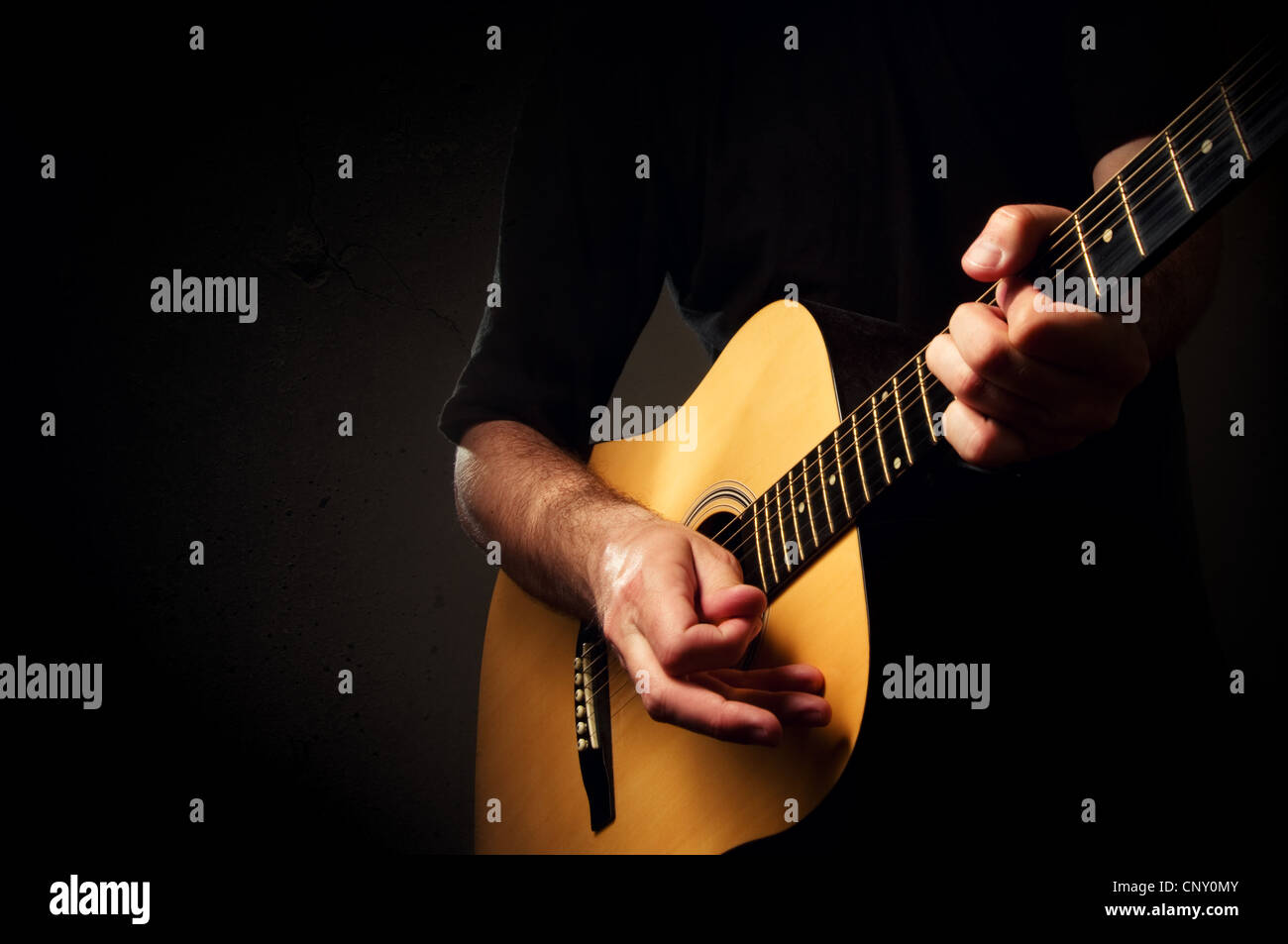 Man spielt eine akustische Gitarre in dunklen Umgebung Stockfoto