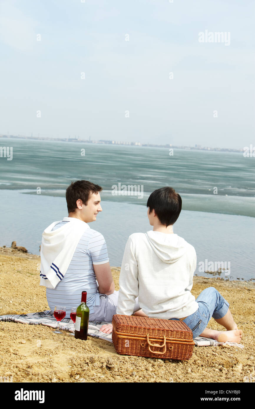 Vertikale Aufnahme eines homosexuellen Paares auf ein Picknick am See Stockfoto