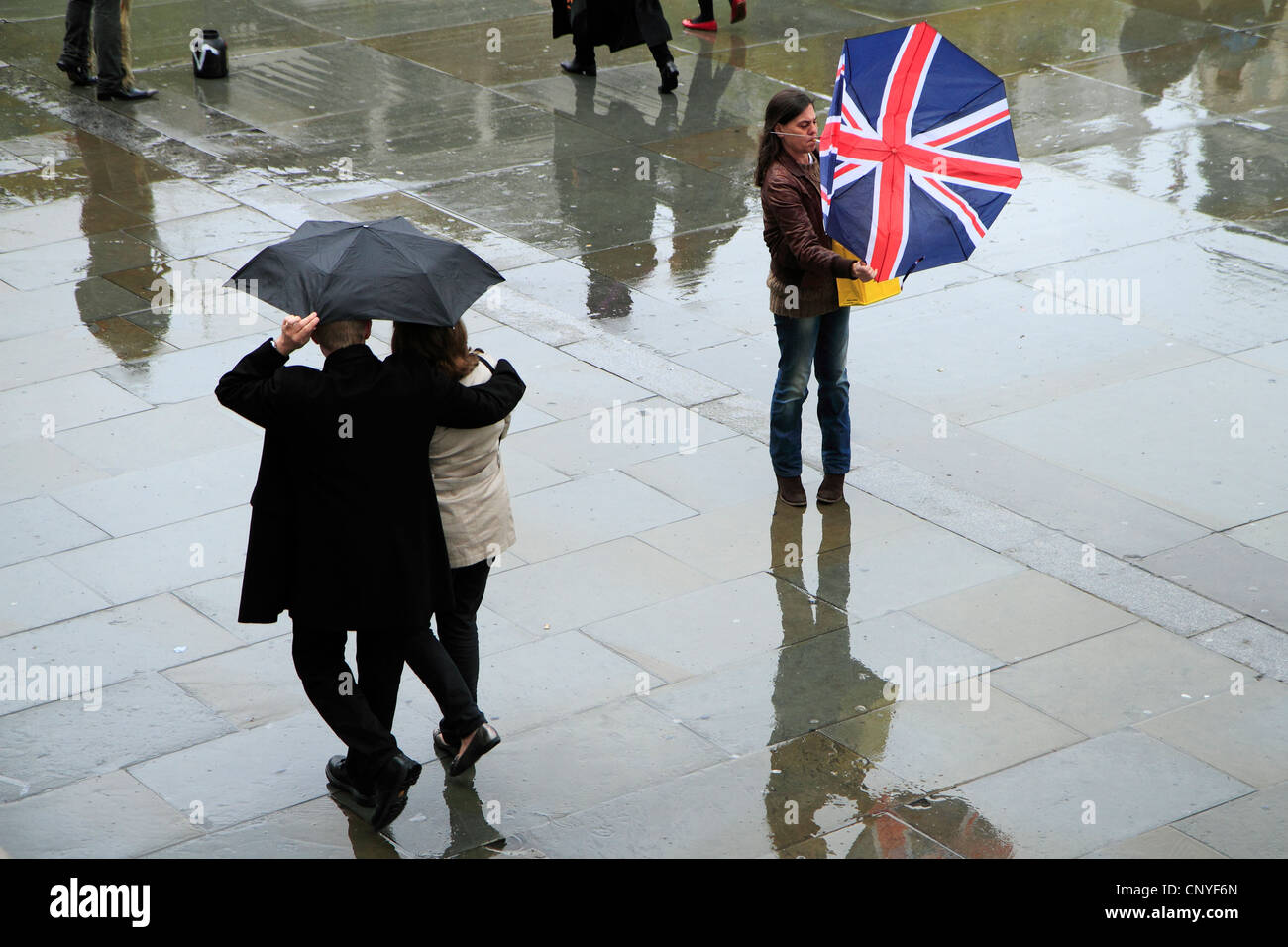 Frau kämpft mit kaputten Regenschirm in Regen, London. Stockfoto