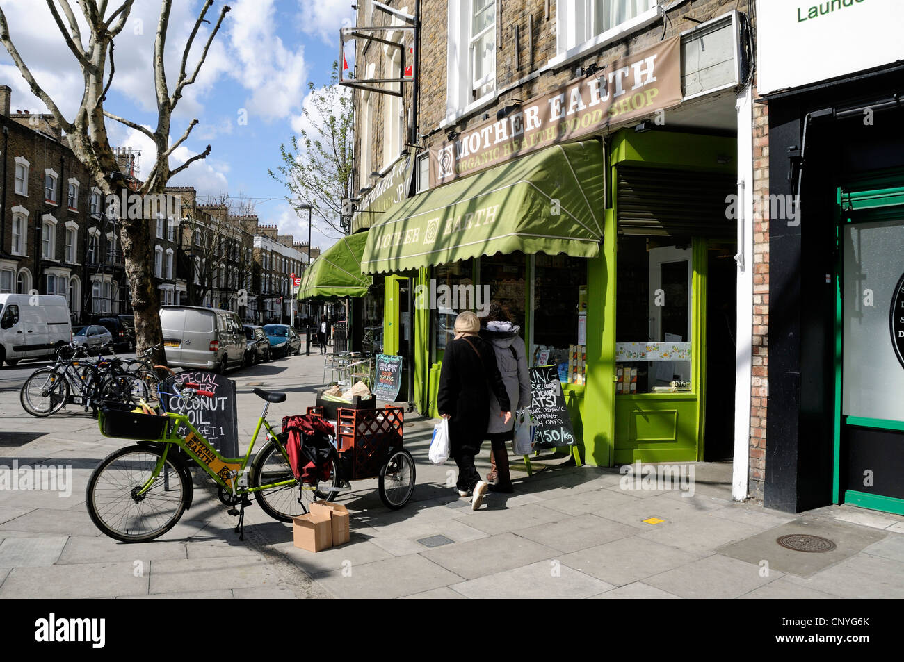 Mutter Erde Naturkost Bioladen mit Lieferung Bike vorne und Passanten, Newington Green, London Stockfoto