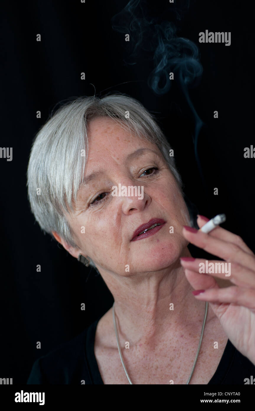 Mittlere gealterte Frau raucht eine Zigarette Stockfoto