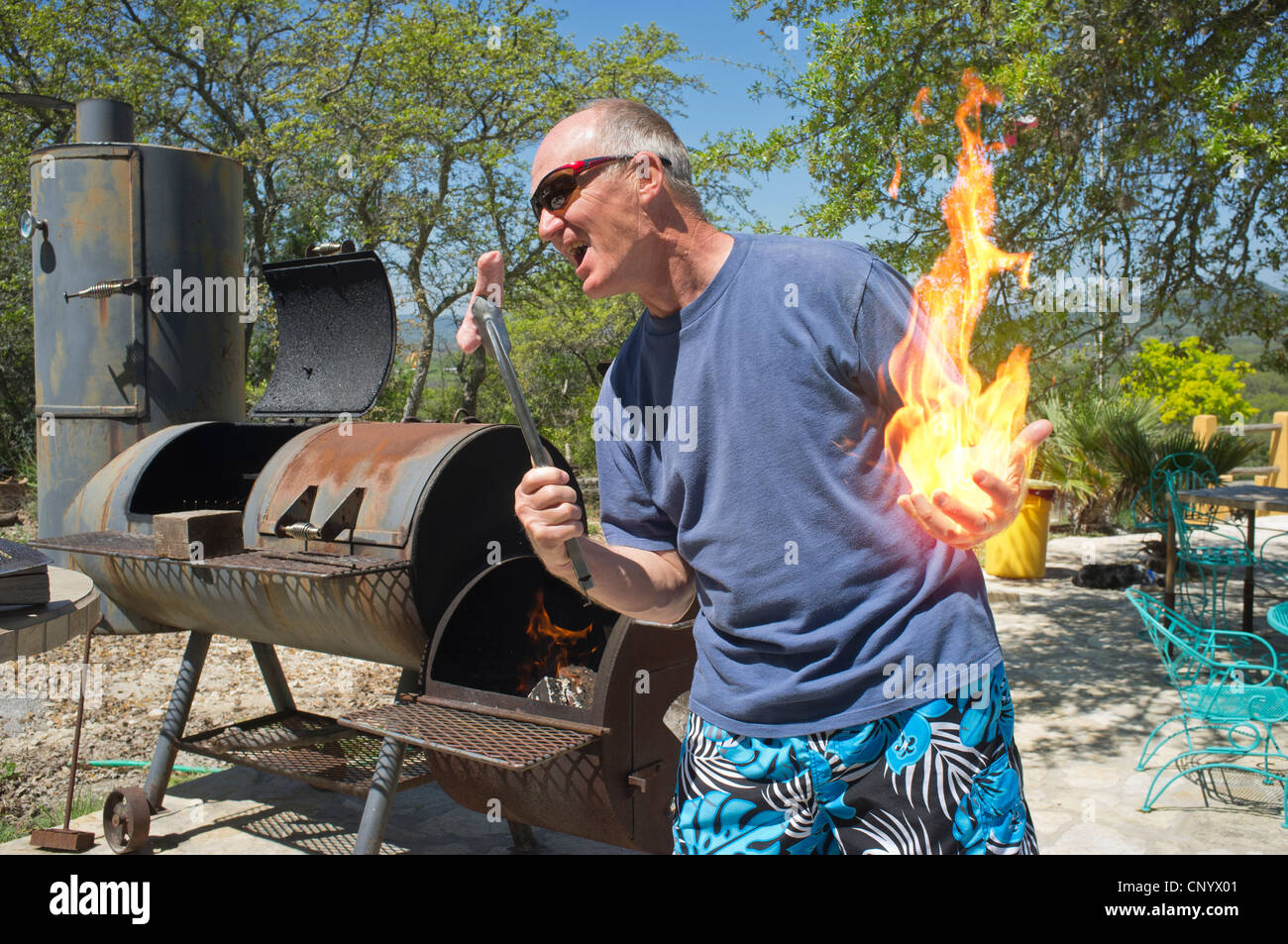Hinterhof BBQ - Verbund von Mann in kurzen Hosen spielen mit Feuer und bratwurst Stockfoto