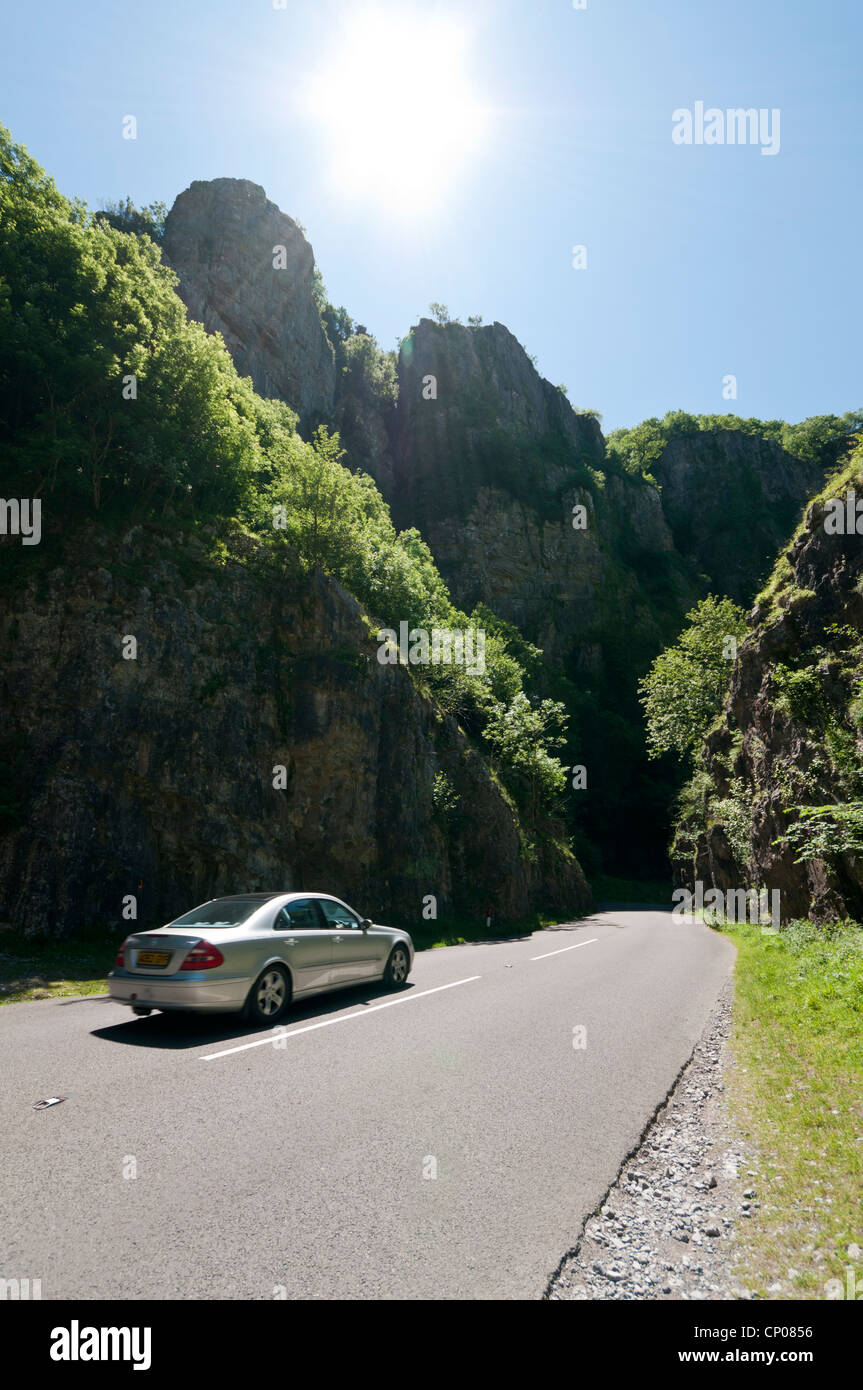 Einem silbernen Auto fahren obwohl Cheddar Gorge in Somerset auf einem sehr sonnigen Tag mit der Sonne im Bild Stockfoto