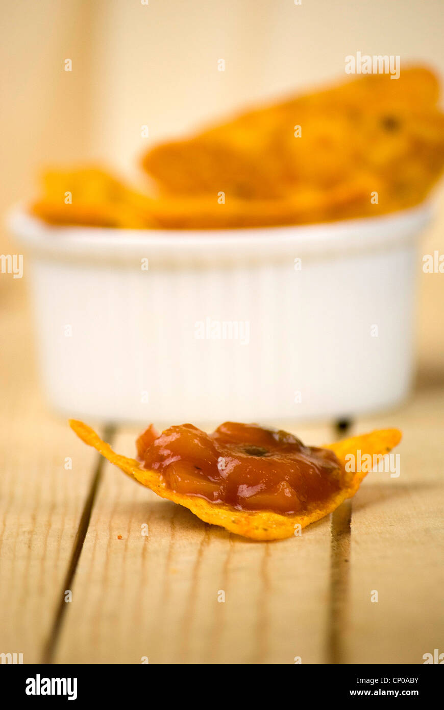würzige Tortilla-Chips und Tomaten-Salsa-Dip über Holzbrett Stockfoto