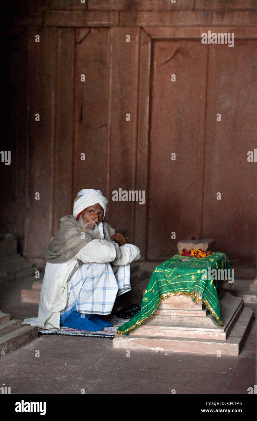 Fatehpur Sikri, Uttar Pradesh, Indien. Alter Mann sitzen durch ein Grab in der Jama Masjid (Moschee Dargah). Stockfoto