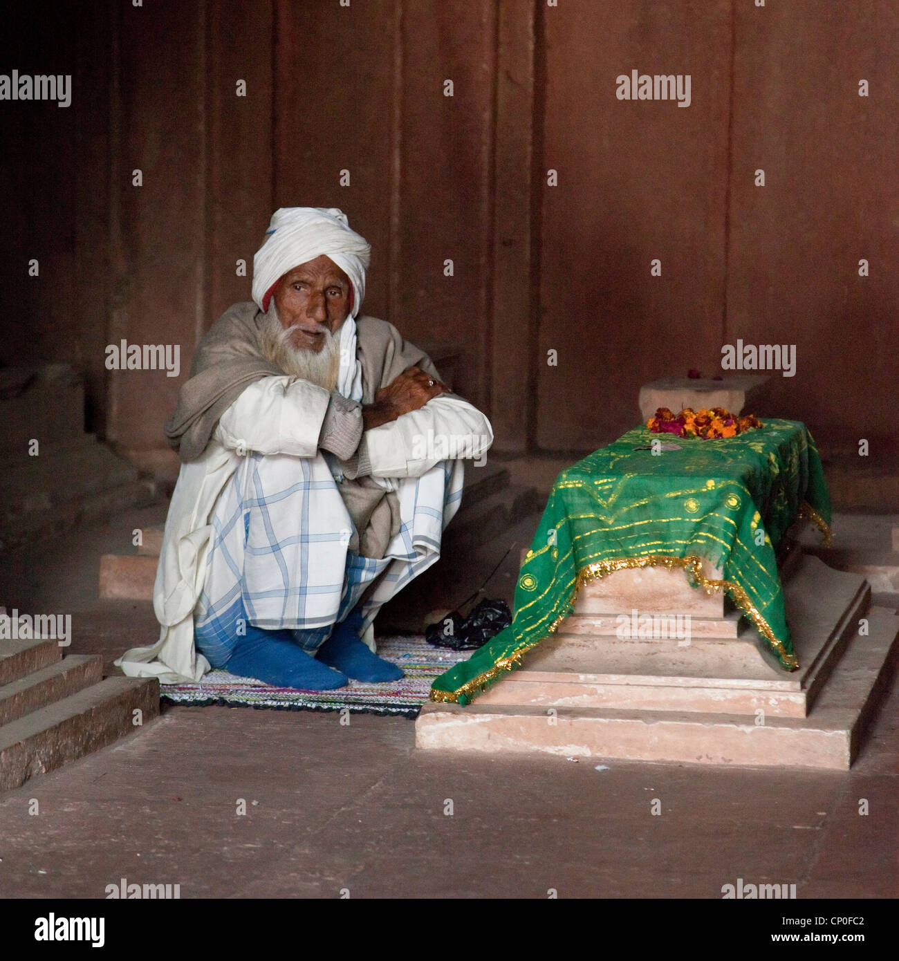 Fatehpur Sikri, Uttar Pradesh, Indien. Alter Mann sitzen durch ein Grab in der Jama Masjid (Moschee Dargah). Stockfoto