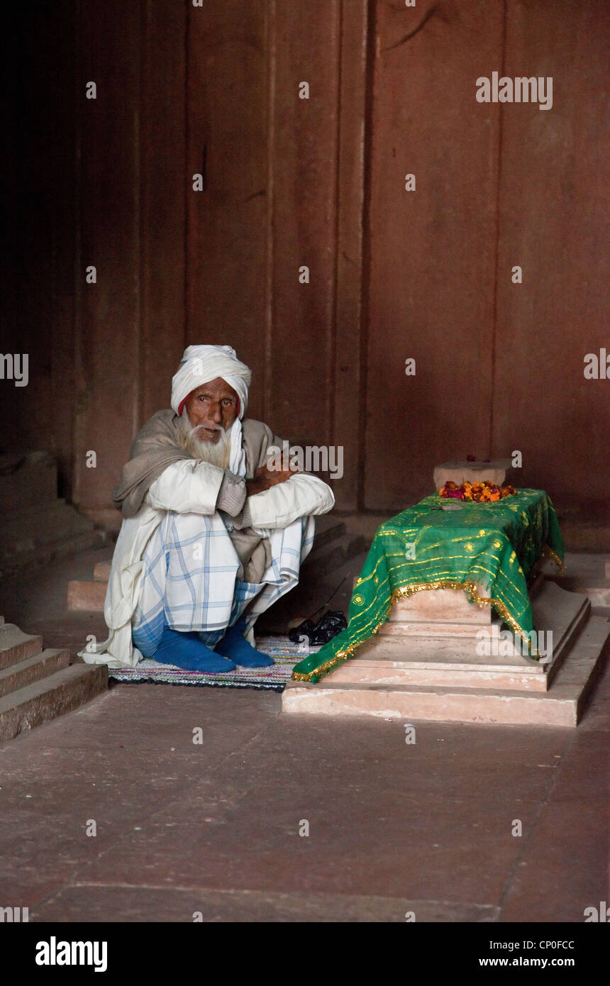 Fatehpur Sikri, Uttar Pradesh, Indien. Alter Mann sitzen durch ein Grab in der Jama Masjid (Moschee Dargah). Stockfoto