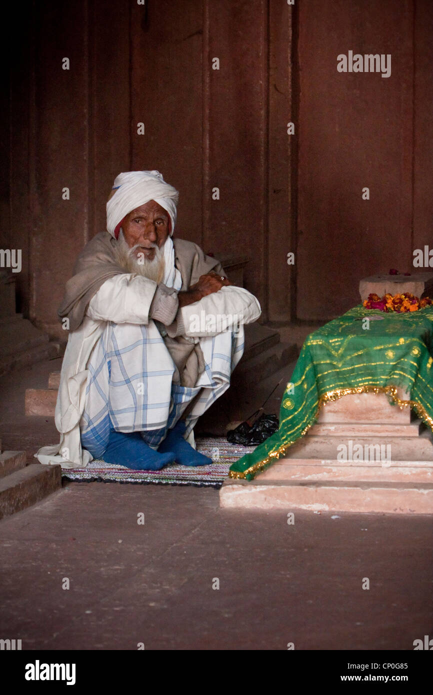 Fatehpur Sikri, Uttar Pradesh, Indien. Alter Mann sitzen durch ein Grab in der Jama Masjid (Moschee Dargah). Stockfoto