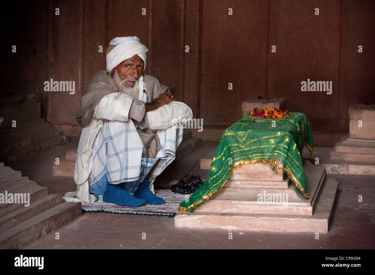 Fatehpur Sikri, Uttar Pradesh, Indien. Alter Mann sitzen durch ein Grab in der Jama Masjid (Moschee Dargah). Stockfoto