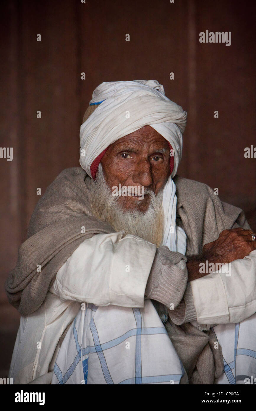 Fatehpur Sikri, Uttar Pradesh, Indien. Alter Mann sitzen durch ein Grab in der Jama Masjid (Moschee Dargah). Stockfoto