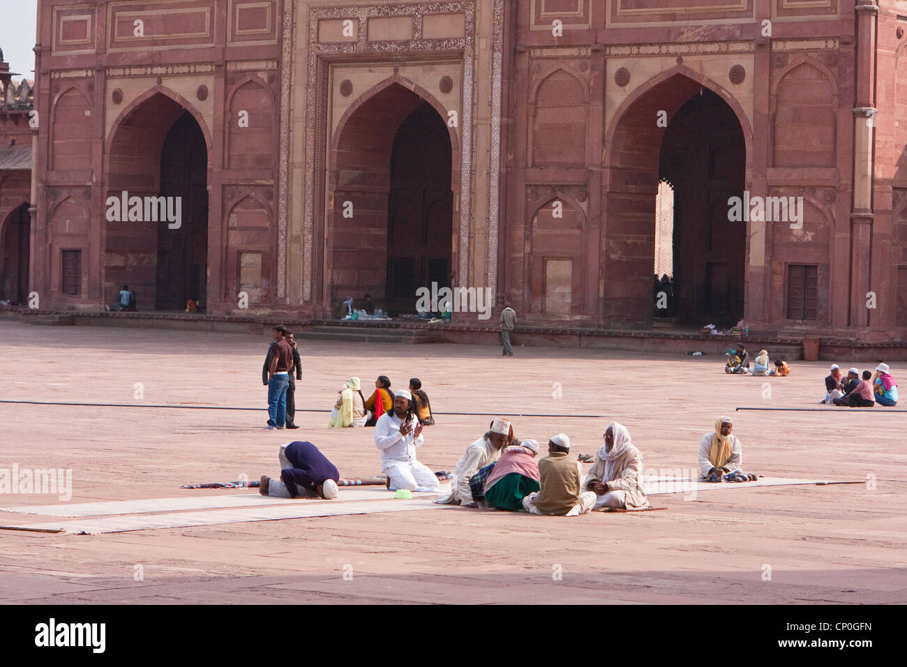 Fatehpur Sikri, Indien. Männer sitzen im Hof der Jama Masjid (Moschee Dargah). Buland Darwaza (große Tor) im Hintergrund. Stockfoto