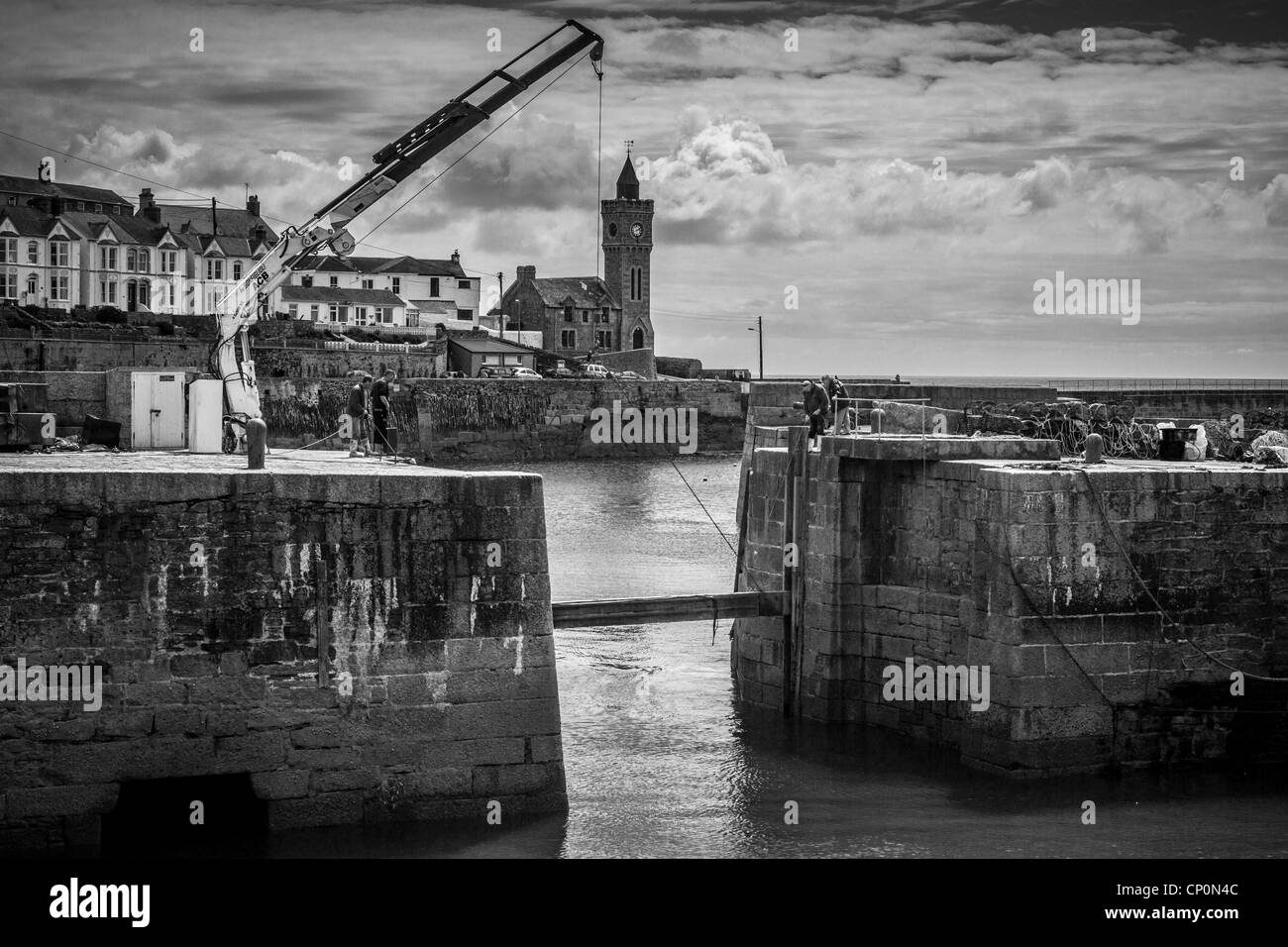 Kran in Aktion am Hafendamm, Cornwall, UK in Monochrom Stockfoto