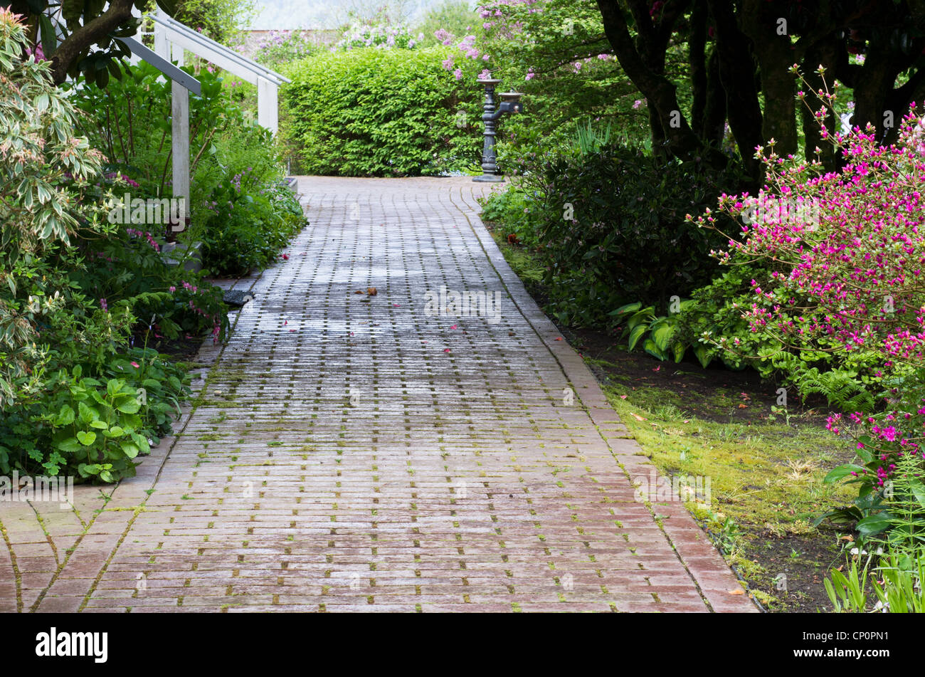 Ein Gartenweg mit Blumen geht durch bewaldetes Gebiet Stockfoto