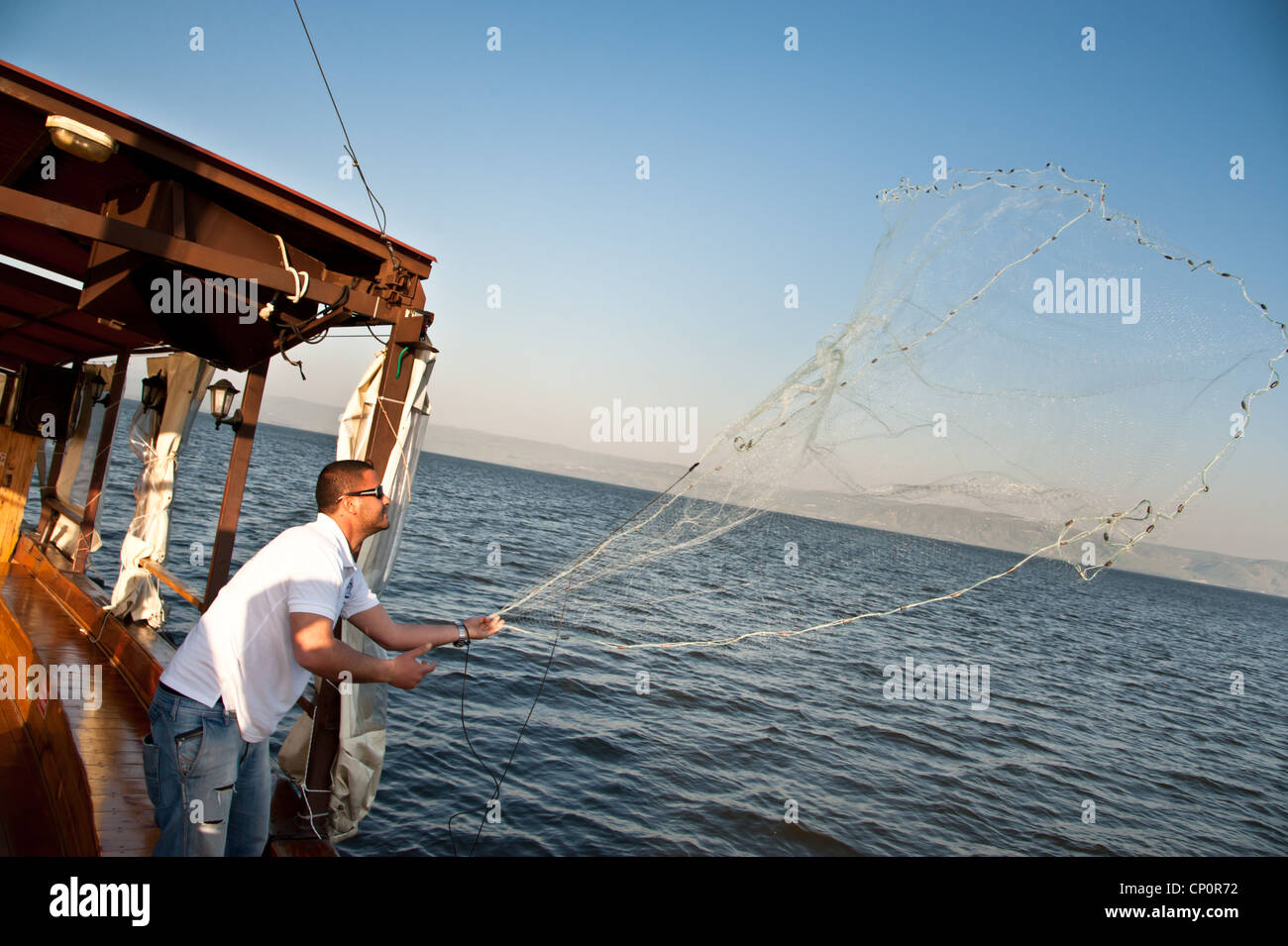 Eine israelische Boot Pilot zeigt gießen ein Fischernetz auf dem See Genezareth. Stockfoto