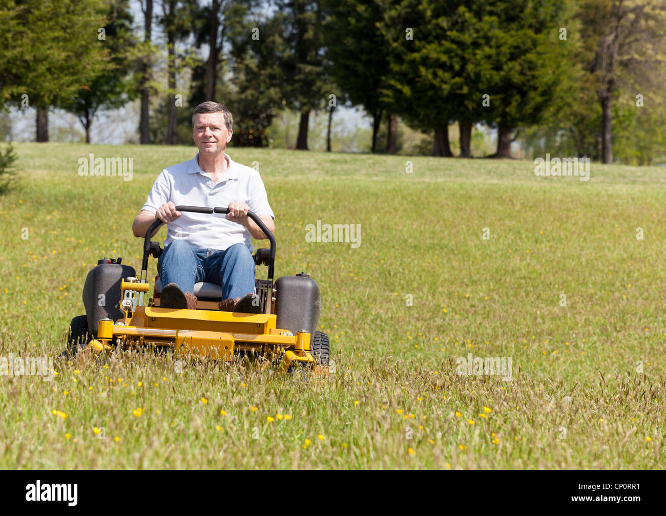 Ältere zog sich männliche Rasen mähen und schneiden das Gras auf einer Sit-on Rasenmäher Stockfoto