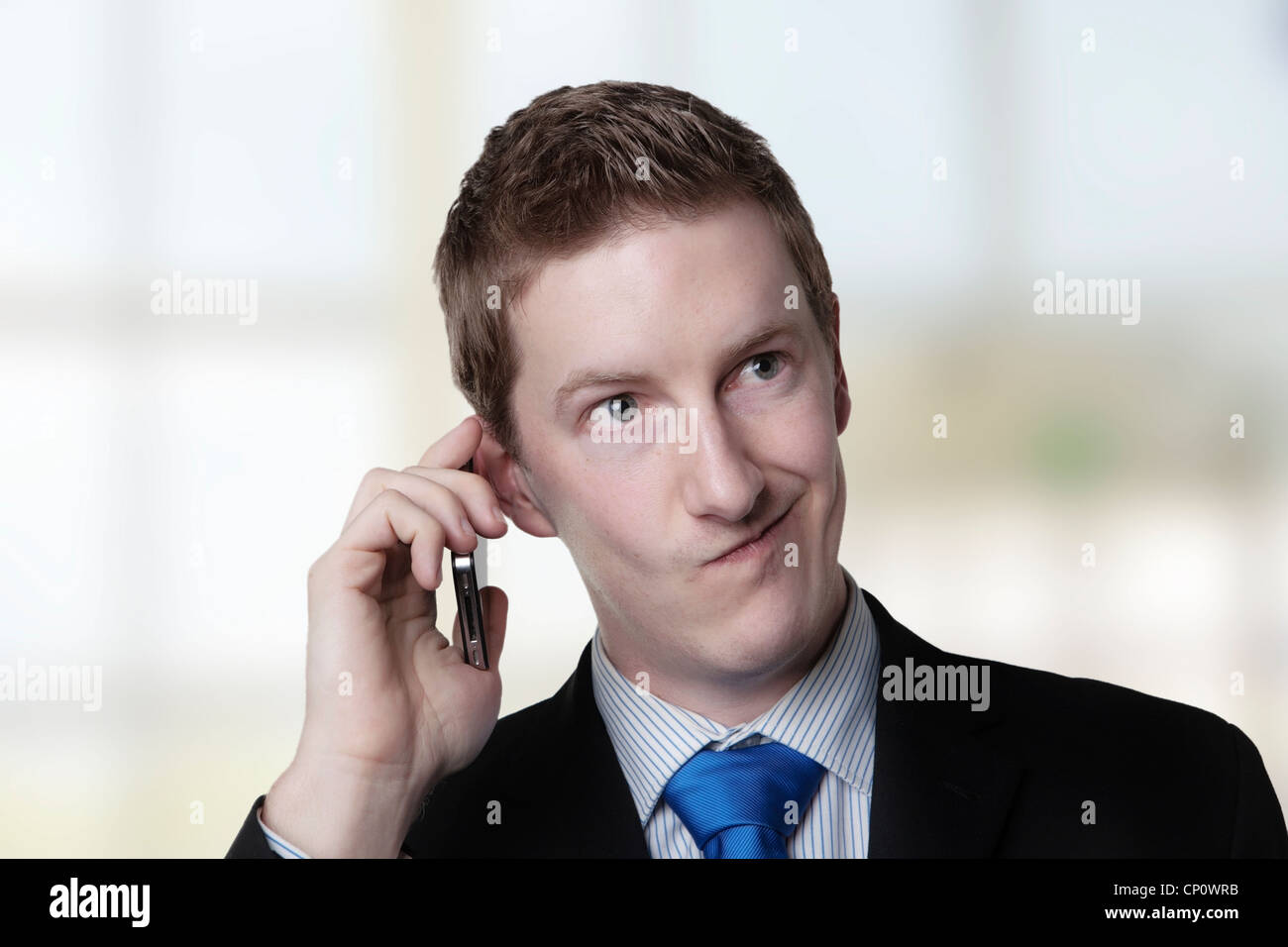 Geschäftsmann nimmt einen Anruf und er sieht aus wie er über etwas nicht sicher Stockfoto