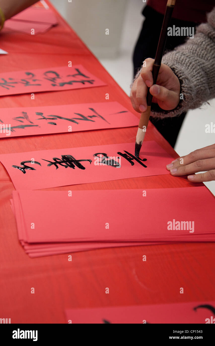 Hände fertige sorgfältig chinesische Buchstaben auf ein Stück rotes Papier während ein Chinese New Year Gehirntätigkeit. Stockfoto