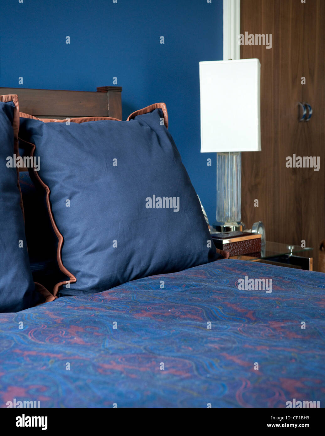 Blau und orange Kissen auf Bett in Addison Road, Großbritannien. Stockfoto