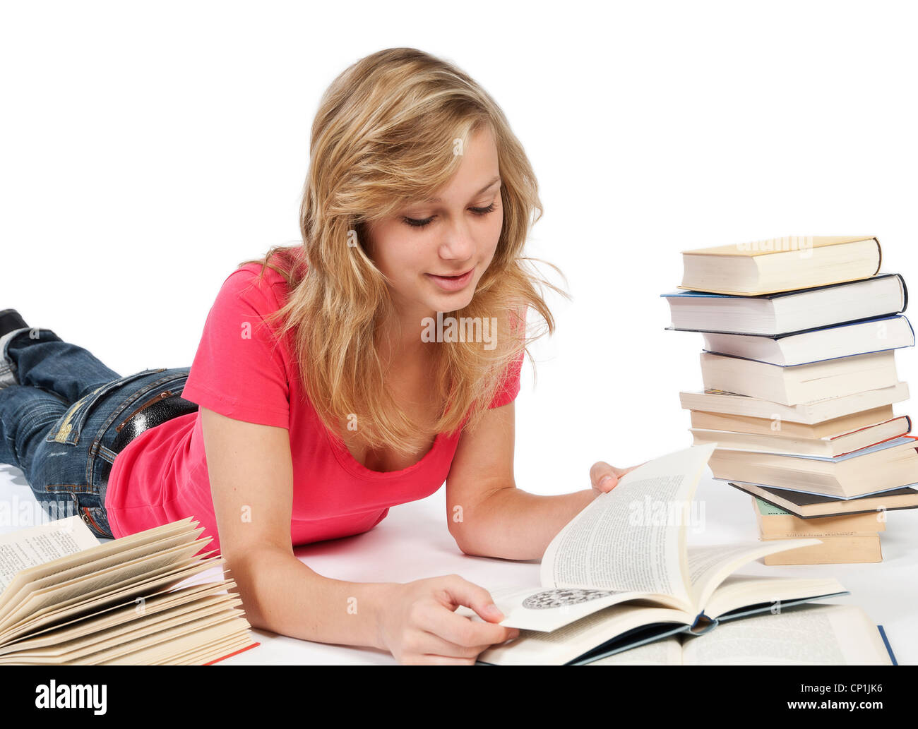 Junge Frau auf dem Boden liegen und ein Buch liest. Weitere Bücher sind um sie herum verteilt. Stockfoto