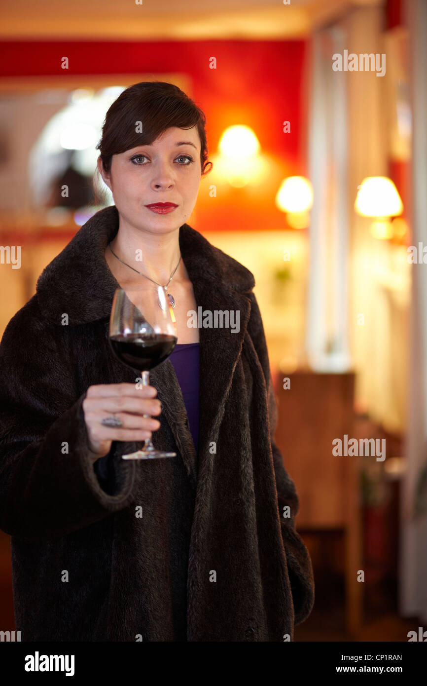 Schöne single-Frau allein mit einem Glas Rotwein mit einem wehmütigen Ausdruck auf ihrem Gesicht. Stockfoto