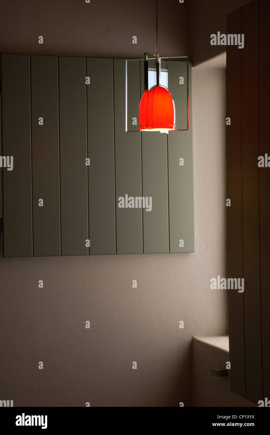 Rote Lampe vor grauen Wand hängen Stockfoto