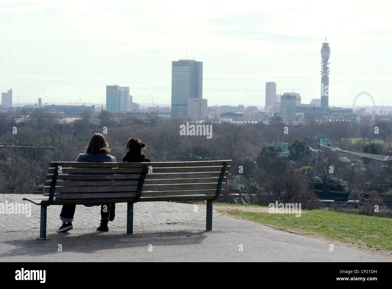 Leute sitzen auf einer Bank mit Blick auf eines der berühmtesten Aussichten auf die Stadt von Primrose Hill, London, NW1, England Stockfoto