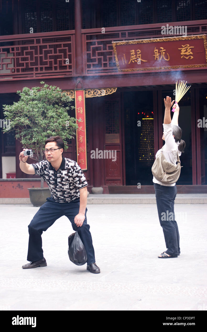 Ein Mann fotografiert und eine Frau beten im Tempel des göttlichen Stadt (Chenghuang Miao), Altstadt, Shanghai, China. Stockfoto