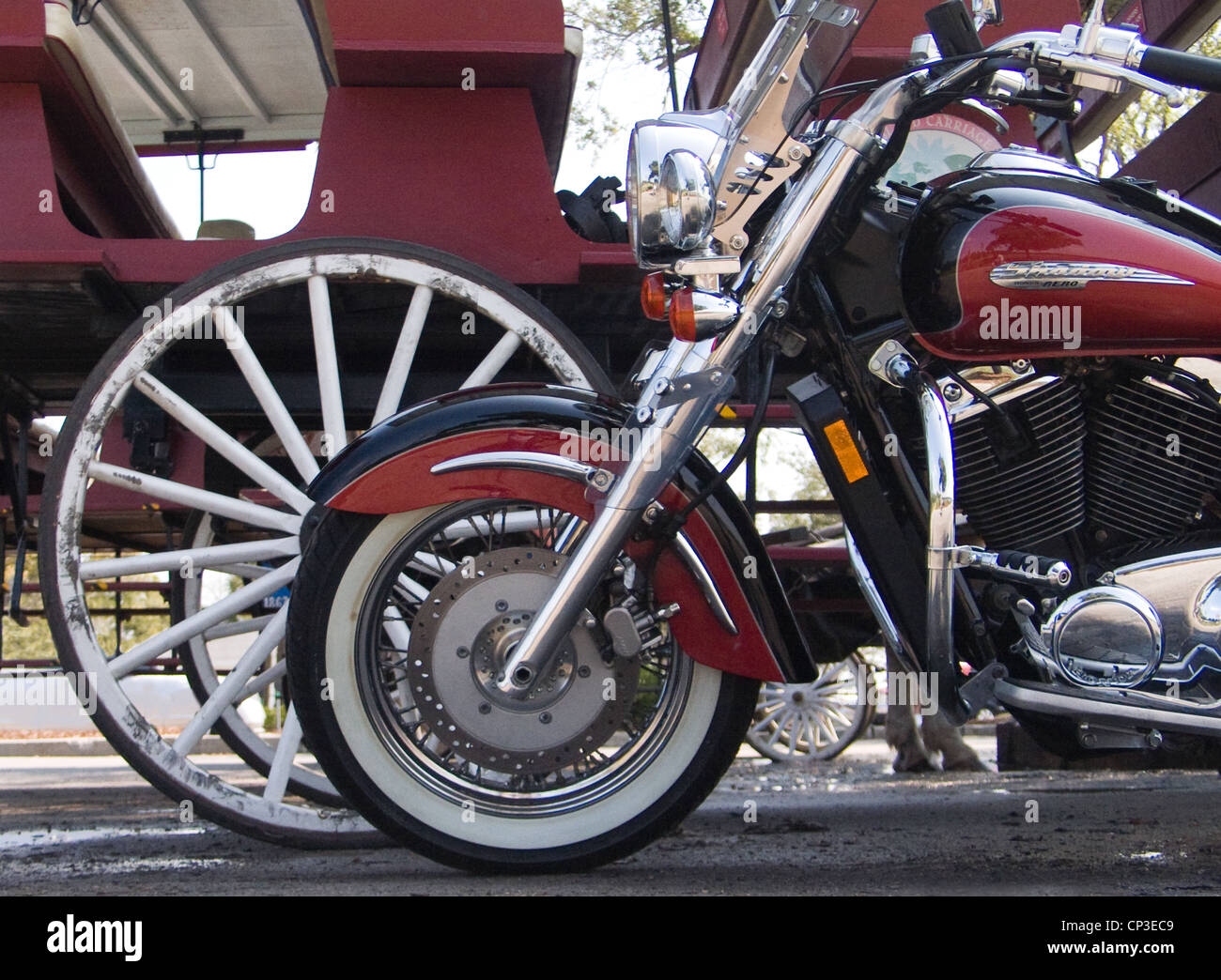 Ein Motorrad ist neben einer Pferdekutsche, Vergleich und Gegenüberstellung der beiden Verkehrsträger geparkt. Stockfoto