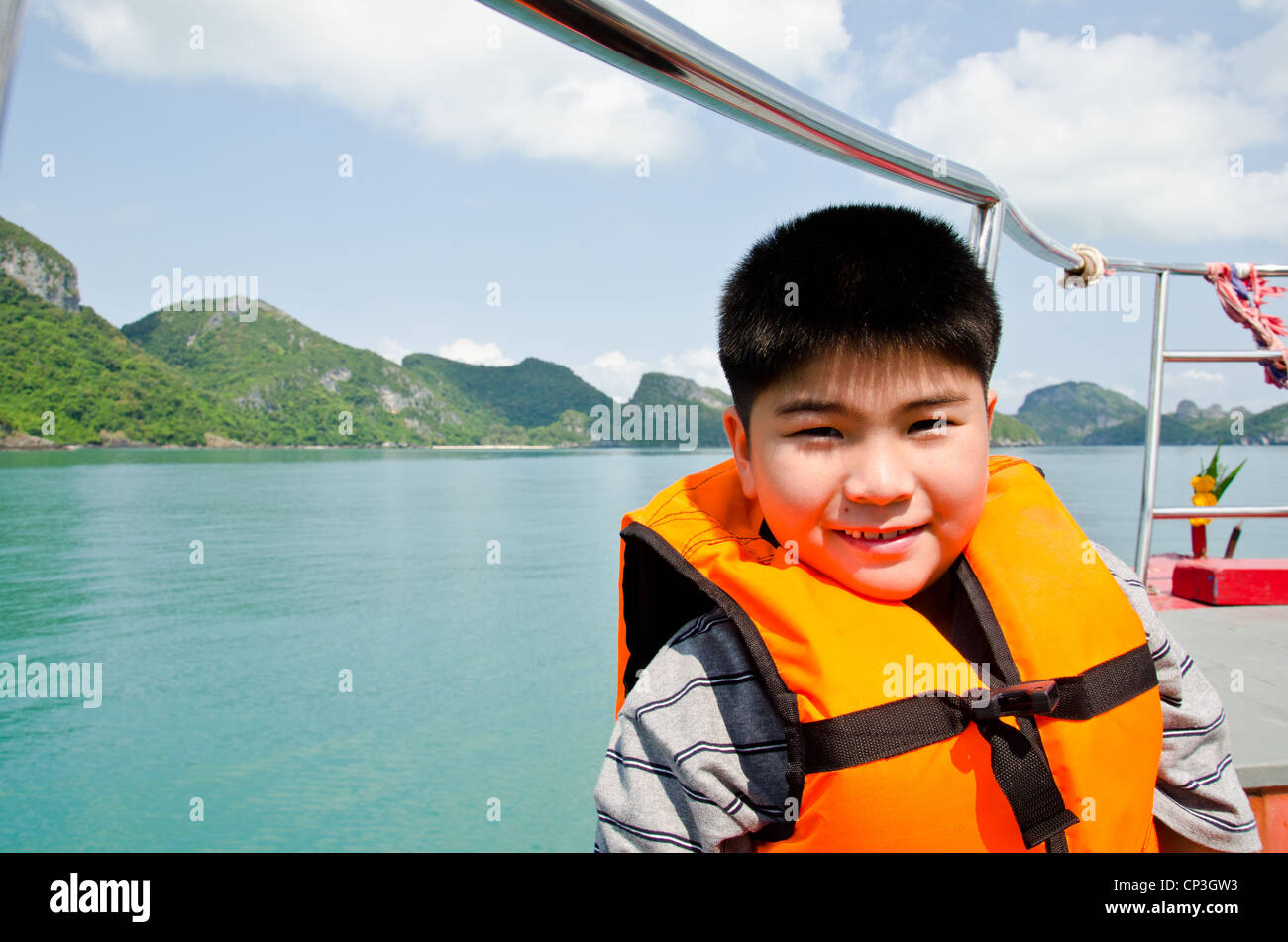 Jungen tragen einer Rettungsweste auf Boote, die im Meer unterwegs sind. Stockfoto