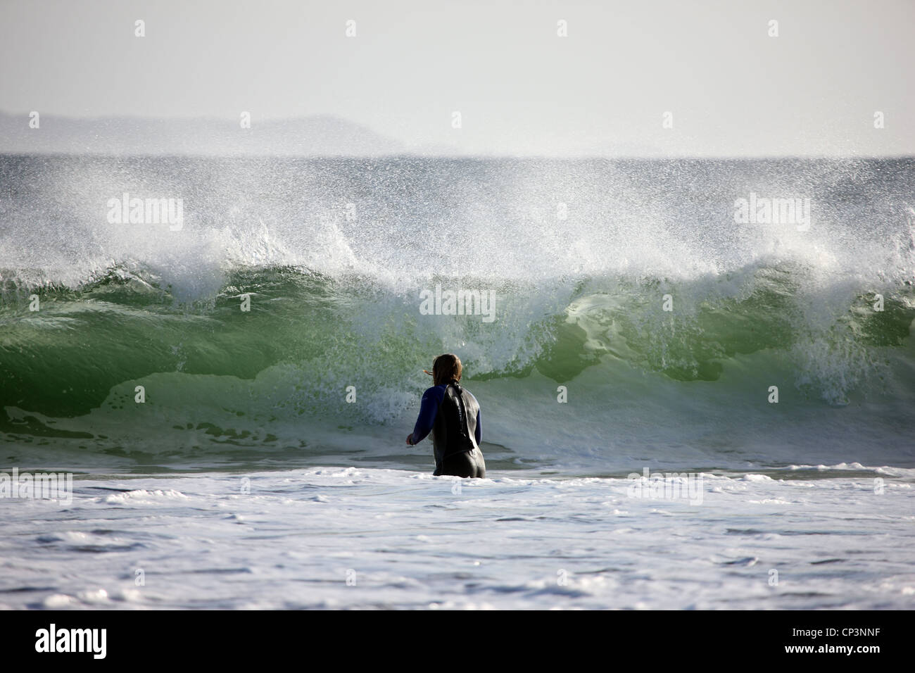 Mädchen tragen Neoprenanzug spielen in riesigen Wellen an der Westküste Schottlands Stockfoto