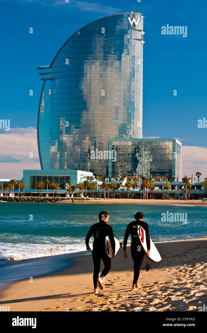 Zwei männliche Surfer am Strand mit W Barcelona Hotel im Hintergrund, Barcelona, Katalonien, Spanien Stockfoto