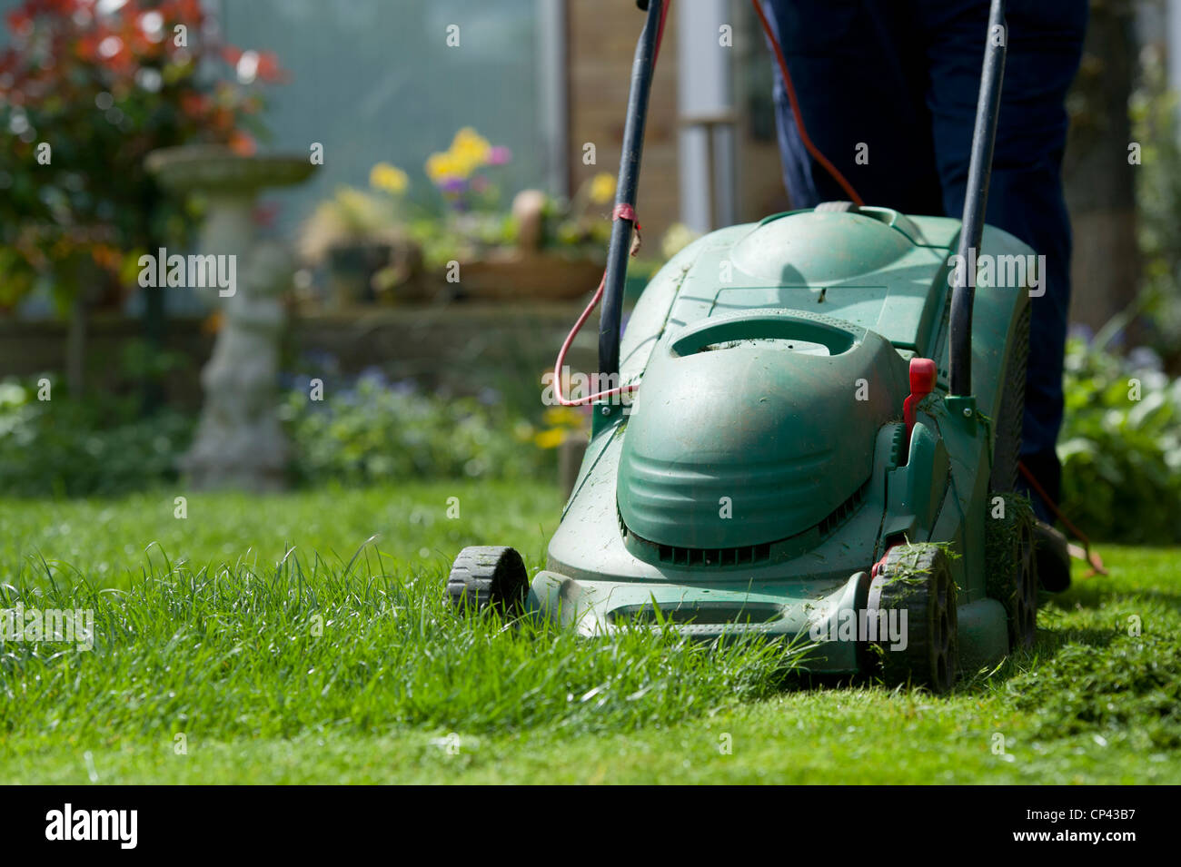 Gärtner, der den Rasen mäht im April. Schneiden das Gras. Gartenbau Jobs Stockfoto