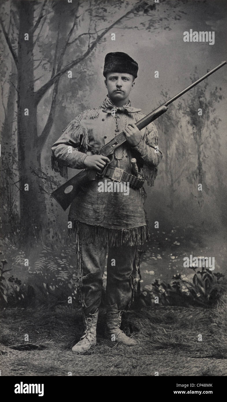 Young Theodore Roosevelt in Hirsch Felle posiert mit einem Gewehr in eine 1885 Studioportrait gekleidet. Im Jahre 1884 schrieb er Artikel über Stockfoto