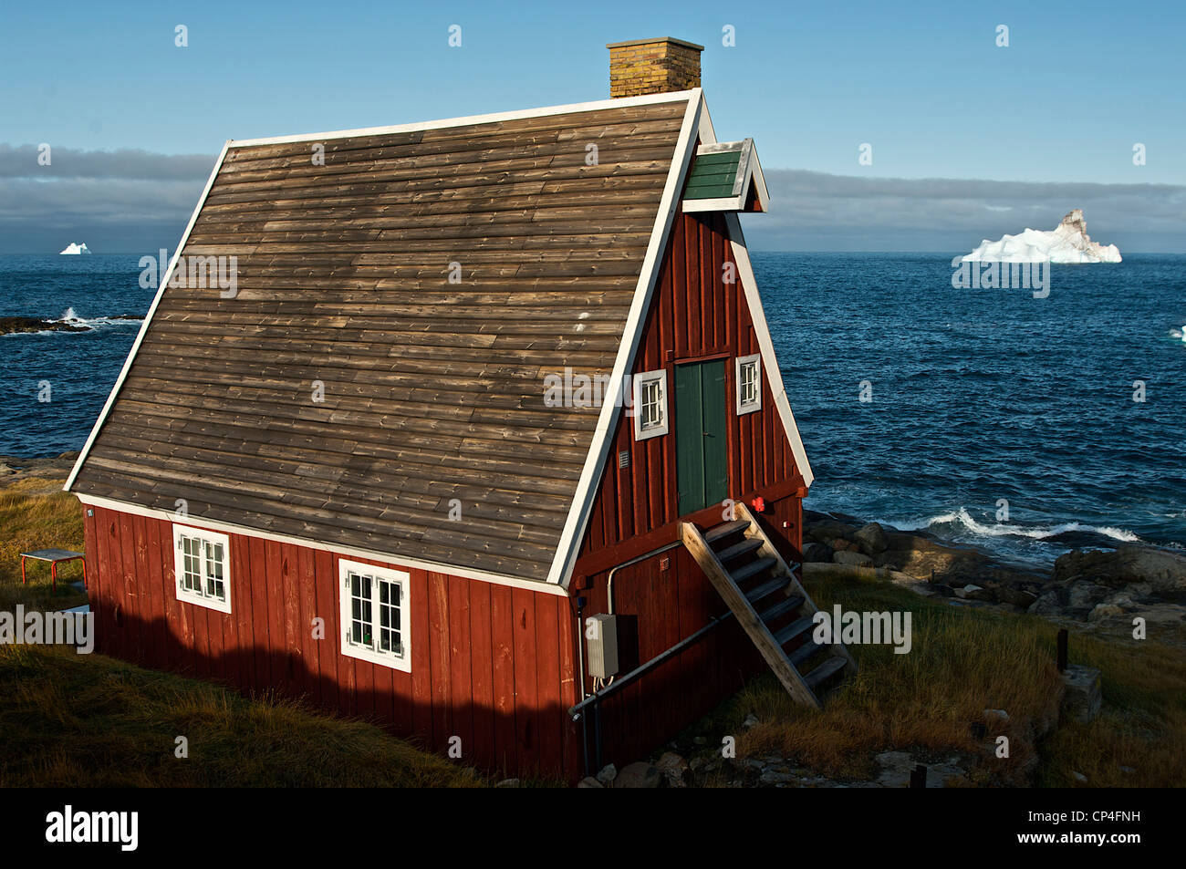 Grönland - Westküste - Qaasuitsup Kommunia - Upernavik. Haus mit Eisberg auf dem Hintergrund. Stockfoto