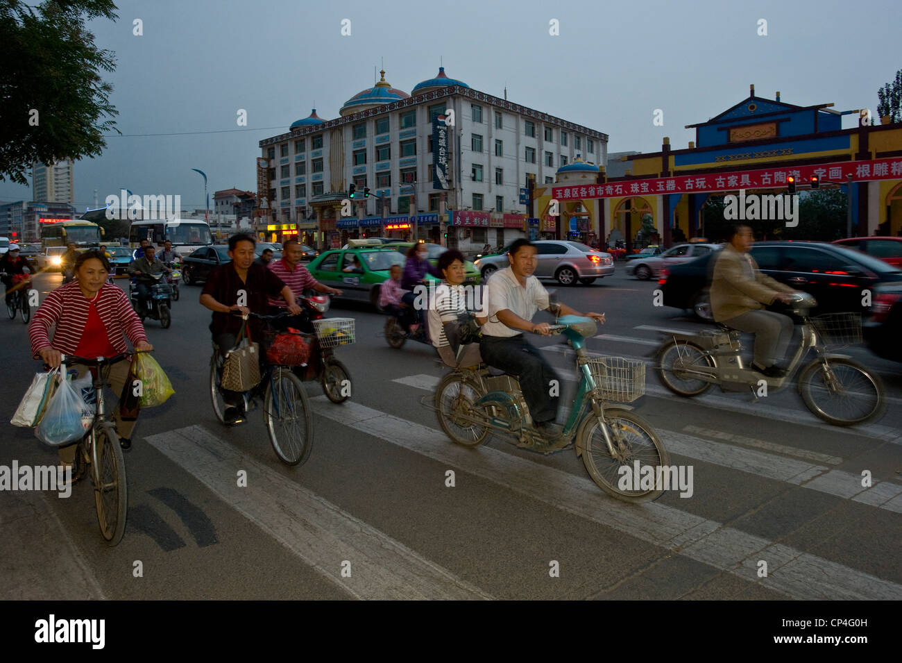 Motorräder, Fahrräder und Autos Fahrt entlang einer der wichtigsten Straßen in Hohhot mit Bewegung verwischen und Blitz in der Abenddämmerung zu füllen. Stockfoto