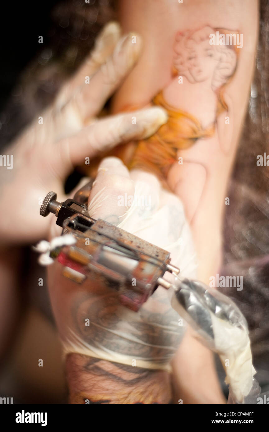 Professionelle tattoo Artist robin Stephens bei der Arbeit - Nahaufnahme Detail Tattoo gun in Aktion Stockfoto