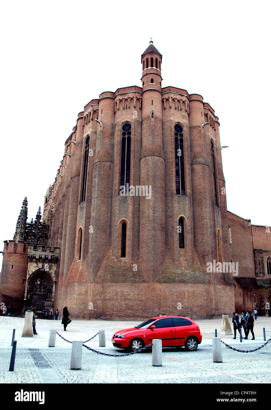 In mittelalterlichen Albi, Frankreich fährt ein kleines rotes Auto hinter großen Backstein-Kathedrale der Stadt bietet fesselnde Kontrast Stockfoto