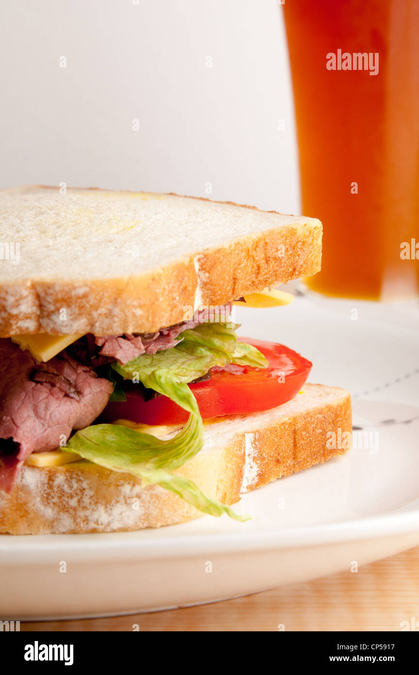 Roast Beef Sandwich mit Salat, Tomaten und Käse mit einem Bier. Stockfoto
