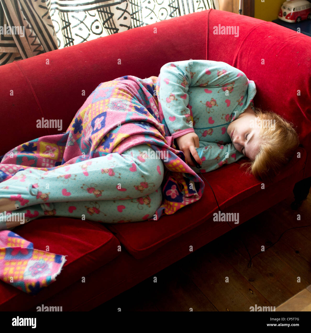 Ein 17 Jahre alter Teenager-Mädchen tragen ein "Strampelanzug" Pyjama  Strampler liegen auf einem Sofa-SMS auf ihr Handy UK Stockfotografie - Alamy