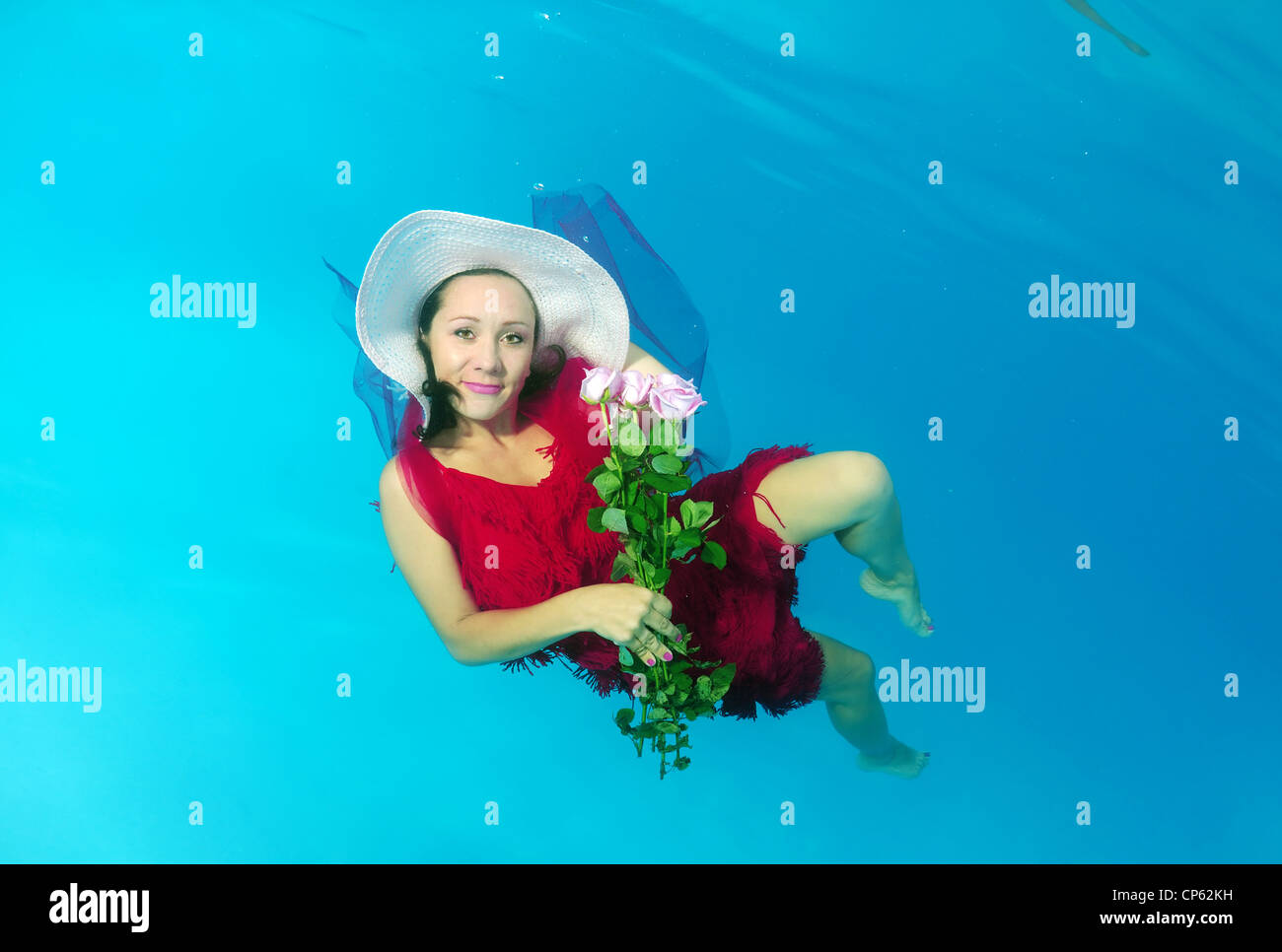 Eine junge Frau mit großen Haar posiert in einem Pool unter Wasser Stockfoto