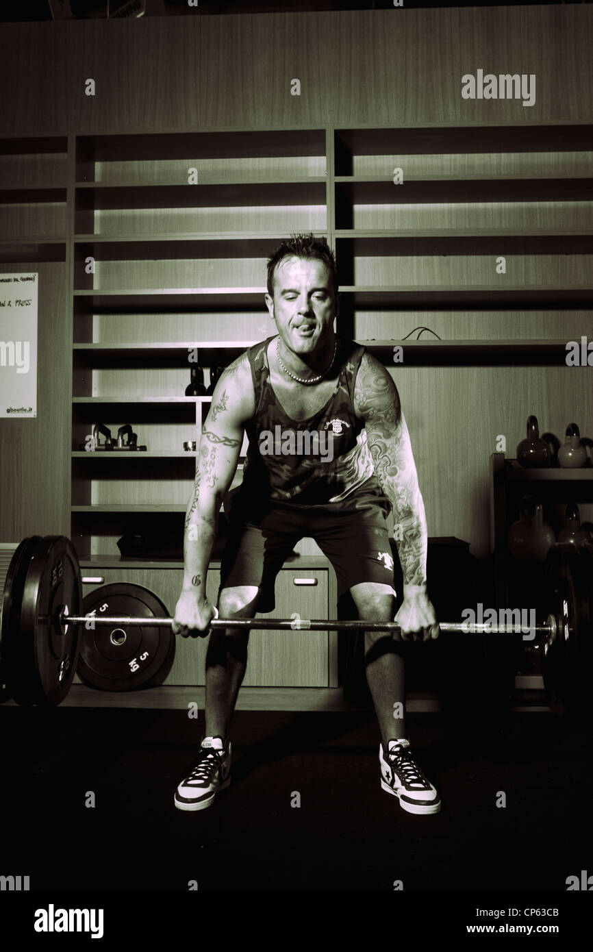 Mann mit Tattoos beim Crossfit Training im Fitnessstudio Gewichte heben Stockfoto