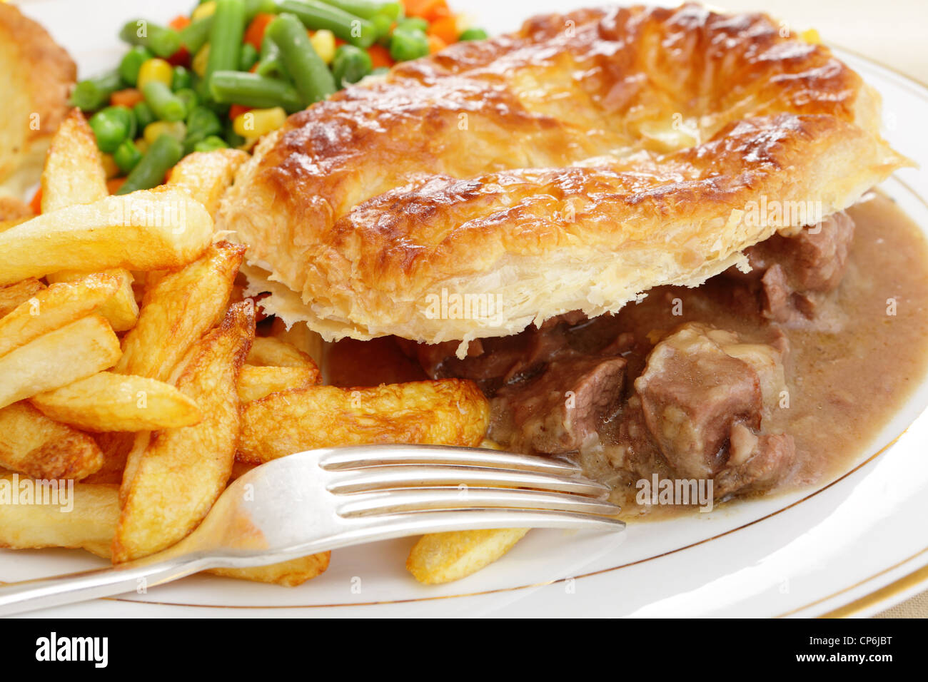 Eine Mahlzeit eine hausgemachte Steak und Kidney Pie mit französischer gebratene Kartoffelchips und Mischgemüse Stockfoto