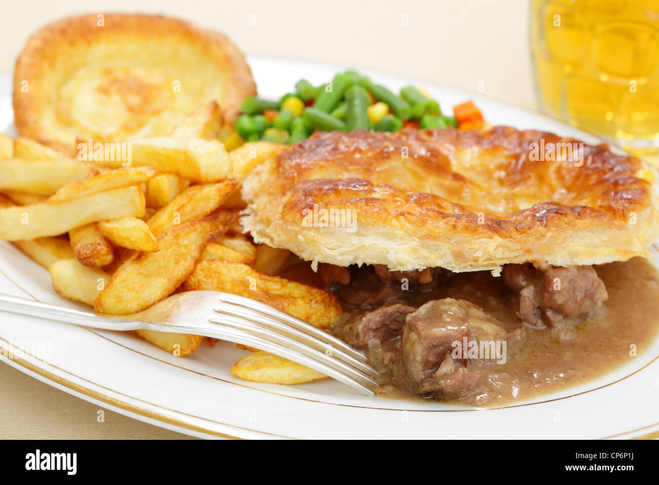 Eine Mahlzeit eine hausgemachte Steak und Kidney Pie mit französischer gebratene Kartoffelchips Yorkshire Pudding und Mischgemüse Stockfoto